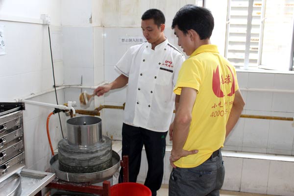 煌旗石磨肠粉培训师傅教学员如何使用石磨机磨米浆